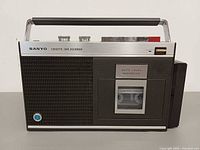 Front view showing speaker grille, cassette window, branding and handle