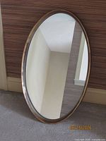 Front view of oval mirror leaning against wall