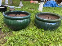 Both green porcelain planting pots side by side in grass