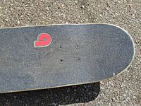 Top of skateboard grip tape with small red green graphic