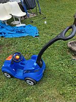 Side view of blue Step2 ride-on car with black push handle attached