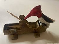 Side view woodpecker on log dispenser with toothpick in beak