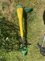 Full view of yellow and green Weed Eater string trimmer on grass