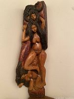 Front view of full wood sculpture showing three human figures