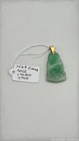 Front view of carved jade Buddha pendant with 14k bail and tag