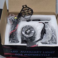 Box contents showing wiring harness, grille, one light, foam packaging