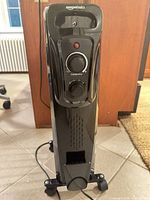 Front view of AmazonBasics radiator heater showing control panel, wheels and cord