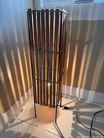 Lamp lit showing bamboo slat shade and metal legs with cord