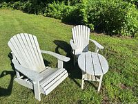 Two Adirondack chairs and side table on lawn