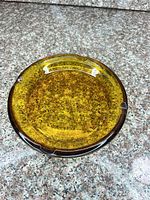 Top angled view showing amber-brown glass ashtray with three rests and mottled interior