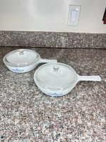 Both handled saucepans with lids on countertop