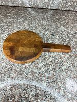 Top view of round end-grain wood board with handle