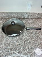 Frying pan with glass lid on countertop