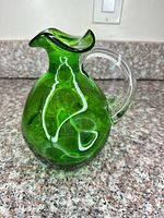 Front and side view showing green body, clear handle, ruffled rim