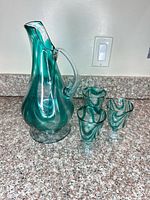 Pitcher and three matching glasses on countertop