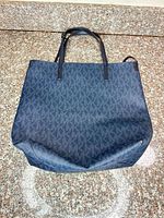 Front view of navy MK monogram tote bag showing overall design and leather handles