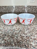 Pair of white milk glass bowls with red athlete graphics on countertop