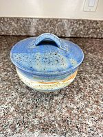 Front view of lidded stoneware bowl showing glaze and handle