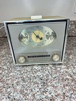 Front view showing clock face, tuning scale, control knobs, RCA Victor branding