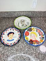 All three hand-painted plates on countertop