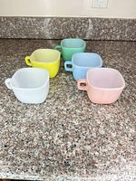 five pastel milk glass cups on countertop