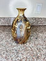 Front view of brown and gold glazed stoneware vase on countertop