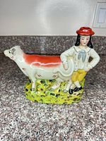 Front view of porcelain cow and handler figurine