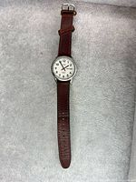 Full view of Timex wristwatch with brown leather strap laid flat