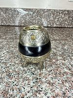 Full view of ornate silver-tone stand front, showing floral relief and black band