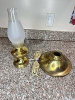 Lamp base, glass chimney inserted, cord coiled, reflector shade beside
