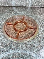 Angled view of pink divided glass tray showing gold rim, center ring, radial dividers