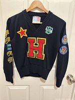 Full front view of navy V-neck sweater with patches visible