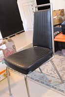 Front/side view of black Chromcraft chair showing vinyl upholstery and chrome frame