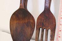 Close-up of spoon bowl and fork head showing teak grain and finish alongside ruler for scale