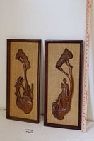 Two framed teak wall hangings side by side