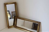 Both gold framed mirrors leaning against wall