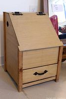 Front and side view showing slanted lid, drawer, side vent hole and metal hardware