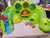 Front view of green dinosaur ball ramp with blue slide and three roll-a-round balls