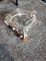 Full view of metal stand with glass bowl on carpet