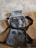 Front view open showing flap, two front zip pockets, adjustable strap