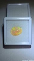 Top view of opal in white plastic display box showing play-of-colour