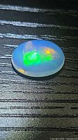 Top view of oval cabochon opal showing play-of-color and inclusion