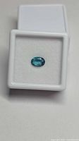 front view of teal blue oval topaz in display case