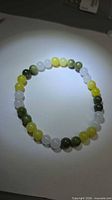 Full view of beaded jade stretch bracelet showing bead colors and arrangement