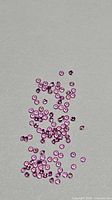 Scattered group of small round pink sapphires on neutral background