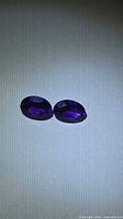 Pair of oval deep purple amethysts on light background