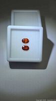 Pair of oval orange gemstones in display box