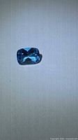 Top view of cushion-cut lagoon blue topaz showing faceting