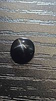 Front view of round black cabochon showing four-ray star