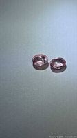 Pair of pink oval cabochon spinels on neutral background